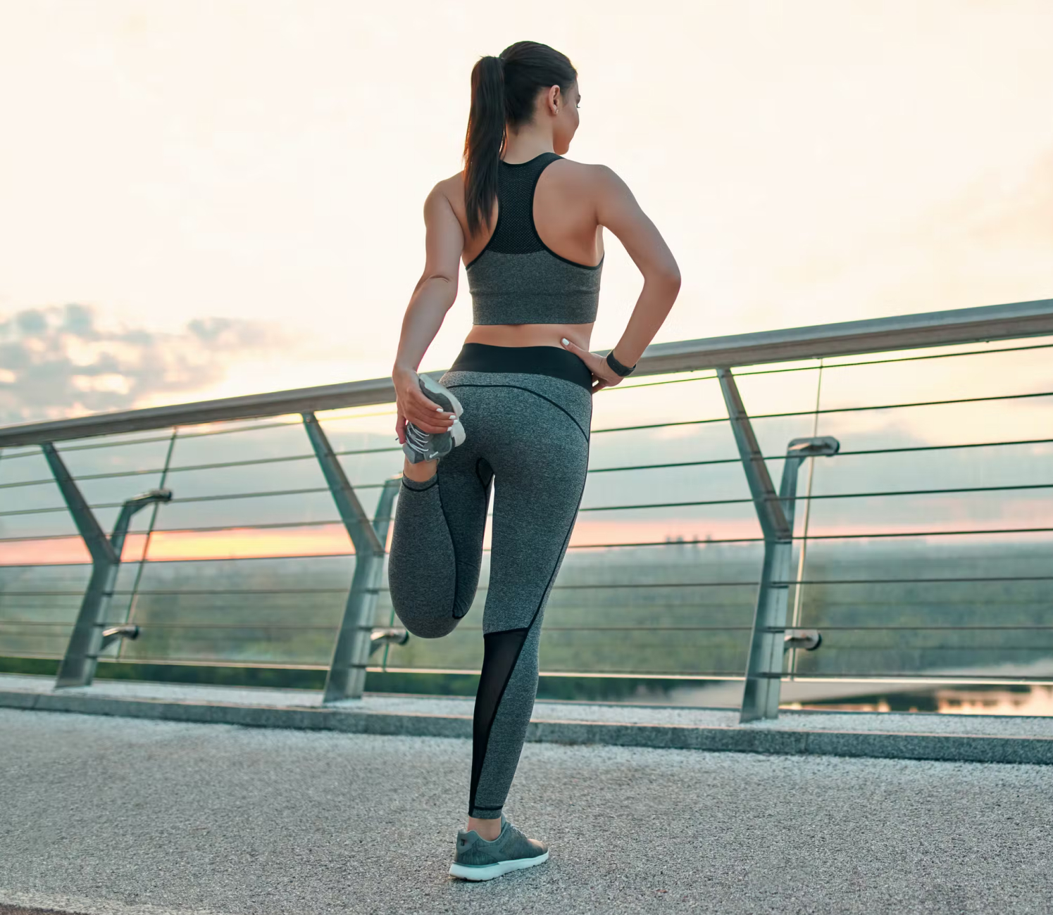 Lifestylebild Joggerin dehnt sich auf einer Brücke