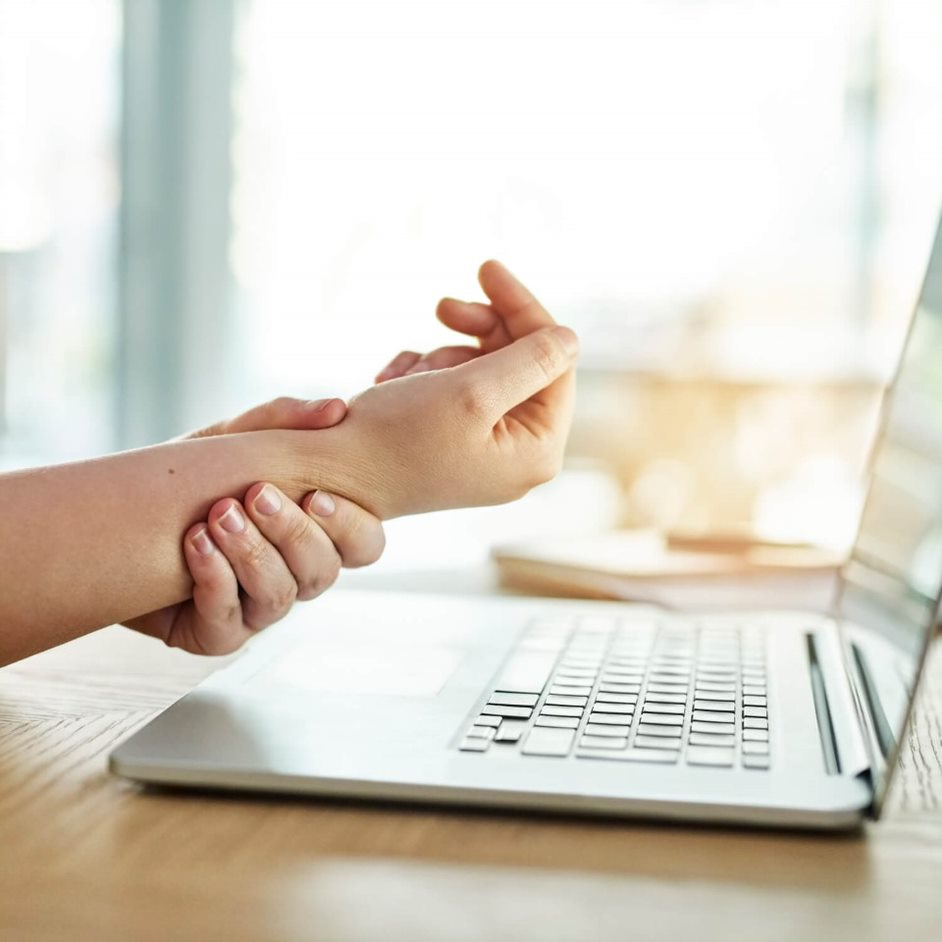 Lifestylebild Frau hält Handgelenk am Laptop